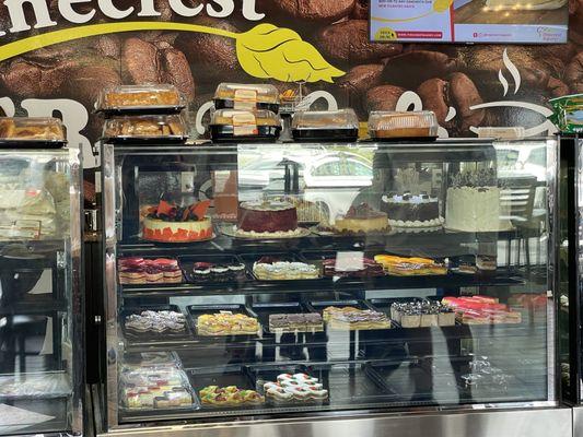 Part of the long display case filled with cakes and pastry's.