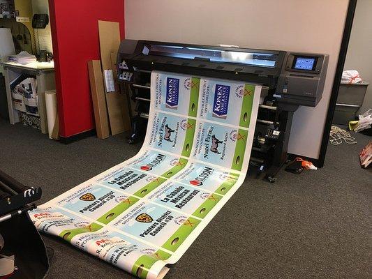 Wide format machine producing adhesive vinyl signs to be applied to coroplast signs.