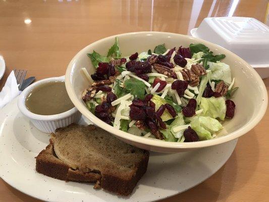 Very fresh salad with vinaigrette salad dressing with a small slice of apple spiced quick bread.