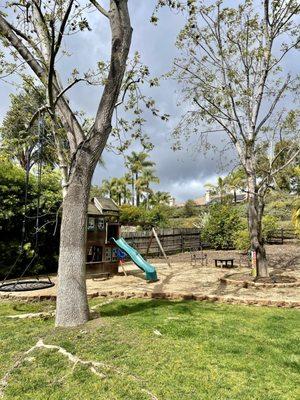 Outside play set and sand area with swings and toys.