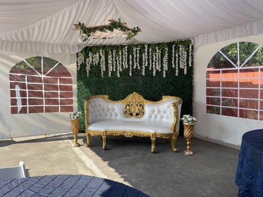 Tent set up with green backdrop and love seat