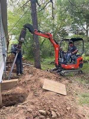 Crew installing steel helical piers through the exterior of a home.