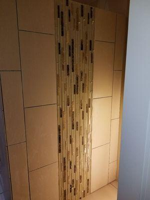 Feature stripe with glass tiles in laid with porcelain tile.