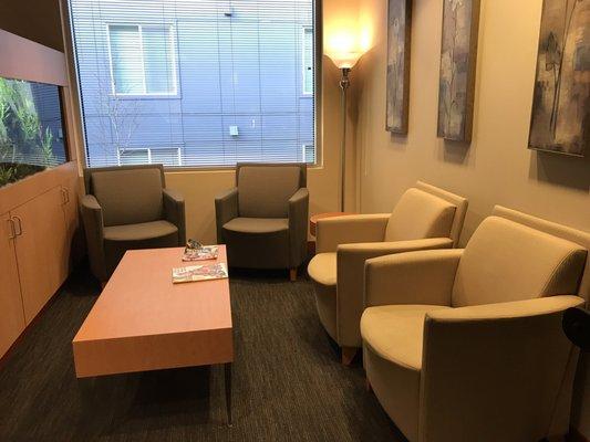 More waiting room seating facing the flat screen tv on the wall and the fish tank!