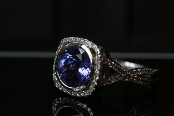 Bezel-set round tanzanite stone in a square halo with twisted split shank band