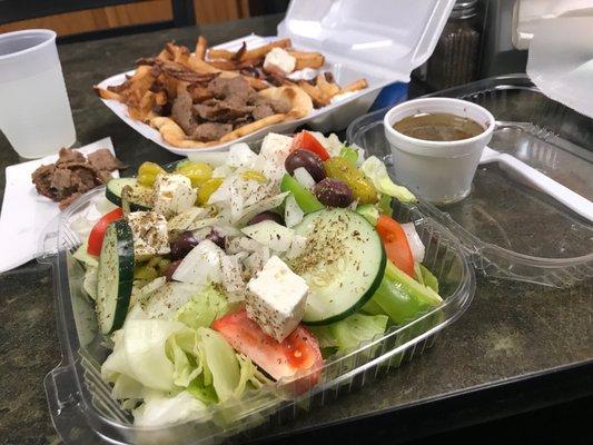 Huge Greek salad with traditional Greek dressing olives, feta, cucumbers and grape vine tomatoes  and lamb gyro plate (background)