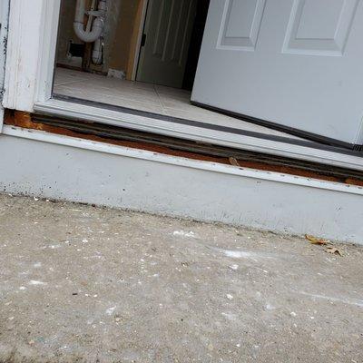 Handyman left gap under exterior door leaving the subfloor exposed. No caulk or membrane was used to keep out water or bugs.