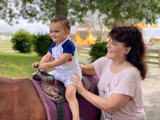 My son getting a horseback ride with grandma.