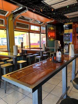 Interior dining room seating (open-air) with an outdoor patio outside to the left