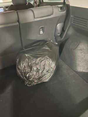 Trash bag full of trash in trunk