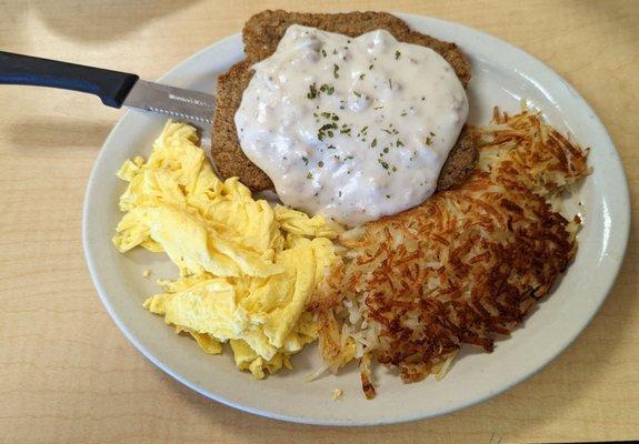 Country fried steak with scrambled eggs and crispy hash browns.  Yum