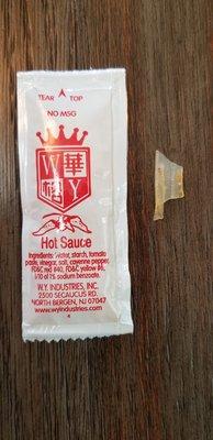 Piece of plastic found in food. Packet of Hot Sauce placed to reference size.