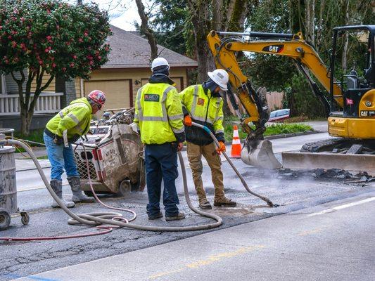 Crew assisting concrete cutter for street job