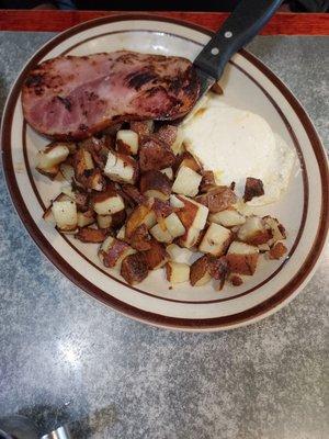 Egg over medium, ham, with American fries, toast.