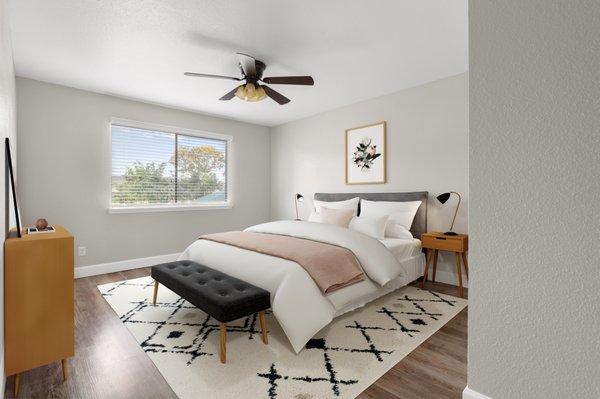 square bedroom showing full bed with ottoman at end. Window with blinds