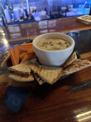 Roasted garlic hummus served warmed with pita chips and carrots