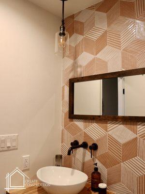 bathroom remodel. decorative bathroom tile wall. Geometric shape tile. floating wood counter with vessel sink. wall mounted sink faucet.