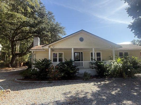 One-story yellow vinyl siding home with large front porch. We are located inside at Suite 101.