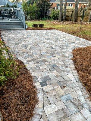 Stone paver walkway and patio area in backyard.