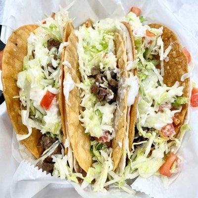 Steak Taco Bravos- Soft Shell Taco inside a Hard Shell. Topped with lettuce, Cheese, tomatoes, and sour cream