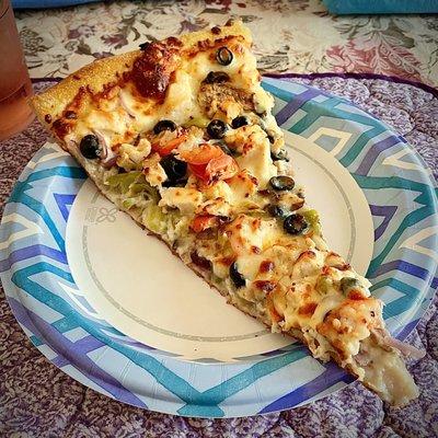 One slice of King Kong size pizza on a dinner-size paper plate.