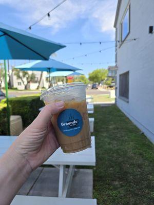 16oz iced coffee outside in the café's outdoor seating area.