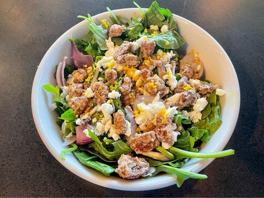 Salad with arugula, spinach, goat cheese, candied pecans, red onion, and orange zest