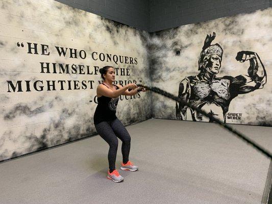 Akron member performing battle ropes in front of our new mural.