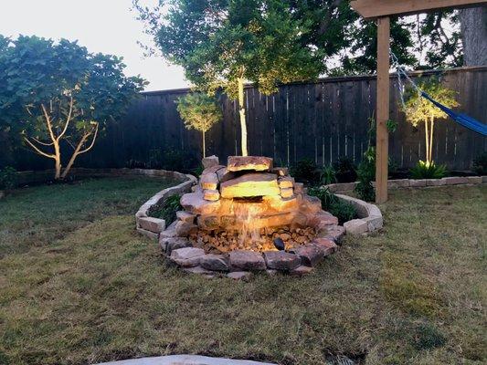 Pondless waterfall fountain features with feature lighting, sod installation and landscaping with pergola in Richmond, TX area.