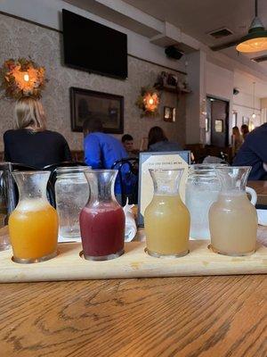 Mimosa Flight (four generous pours of champagne mixed with Blood Orange, Caramelized Pineapple, Myer Lemon, & Passion Fruit)