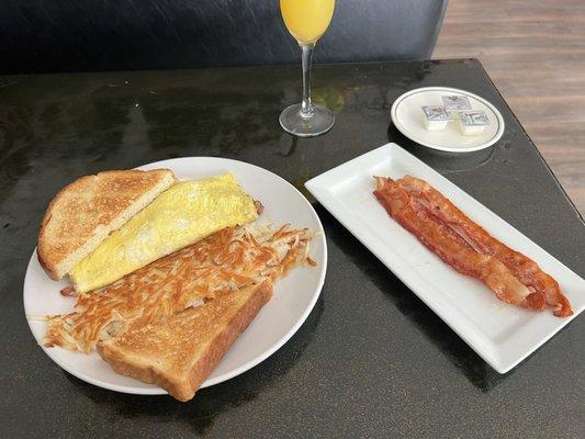 Meat lovers omelette, hashbrowns, bacon, and mimosa