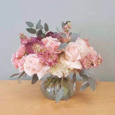 Light Pink flowers arrange in low glass vase with dark pink  hellebores