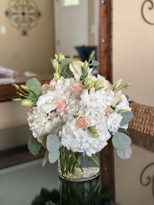 Birthday arrangement with white hydrangeas, peach roses, white lisianthus, and eucalyptus.