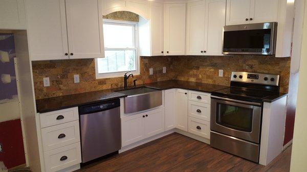 Custom Kitchen with stainless farm sink, lighting, microwave with direct venting, wood look tile flooring