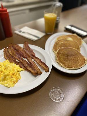 Eggs with cheese, bacon,  Pancakes & orange juice.