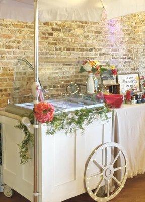 Small wooden ice cream cart at wedding venue featuring 4 flavors.