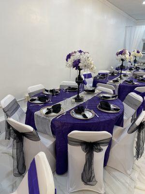 Purple Tablecloth with Silver Runner and chair tie backs. Custom centerpiece with silk flowers.