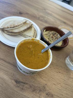 Red lentil soup with a side of pita and hummus