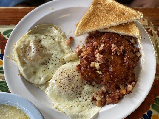 Two eggs over easy, corned beef hash, grits and toast