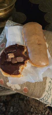 Partially eaten Reese's donut on the left and a maple bar on the right.