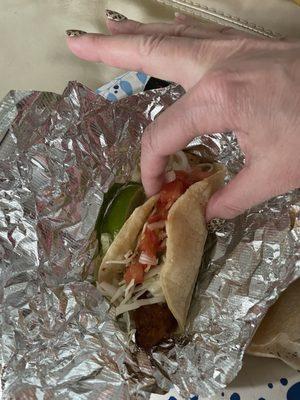 Fish taco with a pathetically small thin piece of fried fish