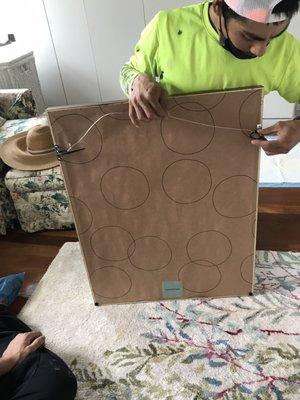 This is a photo of us redoing the hanging wire on the back of the frame ourselves because it was done incompetently at the store.