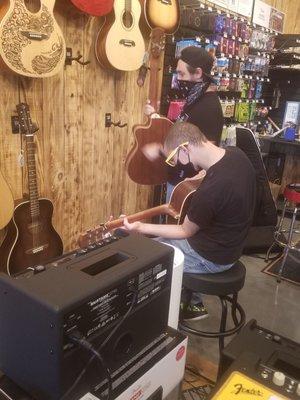 The store manager and my son staying safe and playing chords.