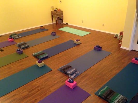 View of yoga studio from the back, facing the teacher's mat at the front. Studio can hold 9 students comfortably.