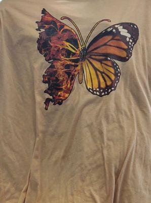 A tan t-shirt with a beautiful butterfly.