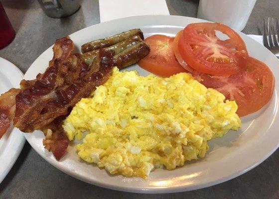 Scrambled  eggs with cheese, bacon AND link sausages. I got tomatoes instead of potatoes.