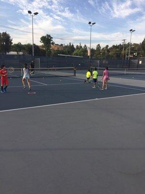 Chillin' while watching kids have fun while learning to play tennis the right way