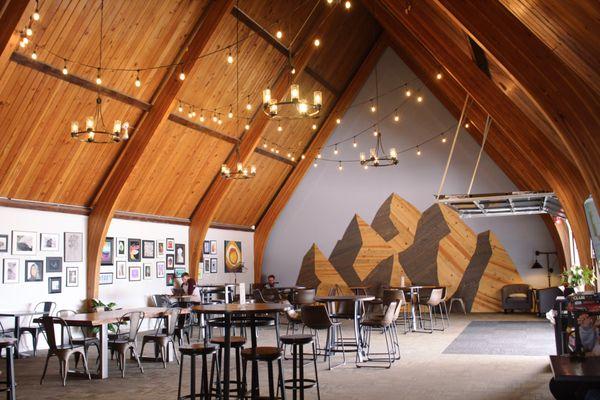 Front Porch Coffee Shop interior with wooden mountain mural in seating area.