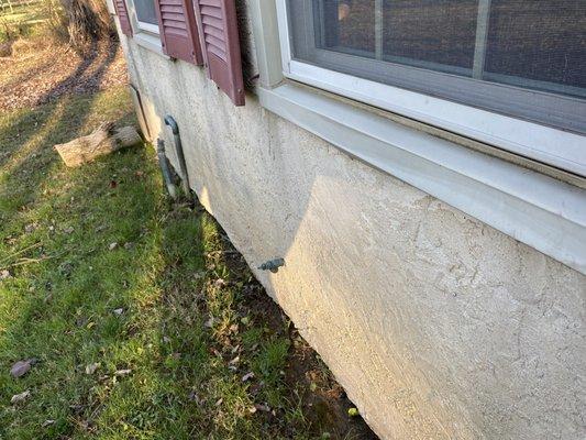 Damage along the bottom of window and a log dropped at the corner of house