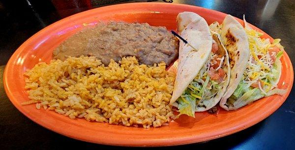 Two ground beef tacos, with rice and re-fried beans